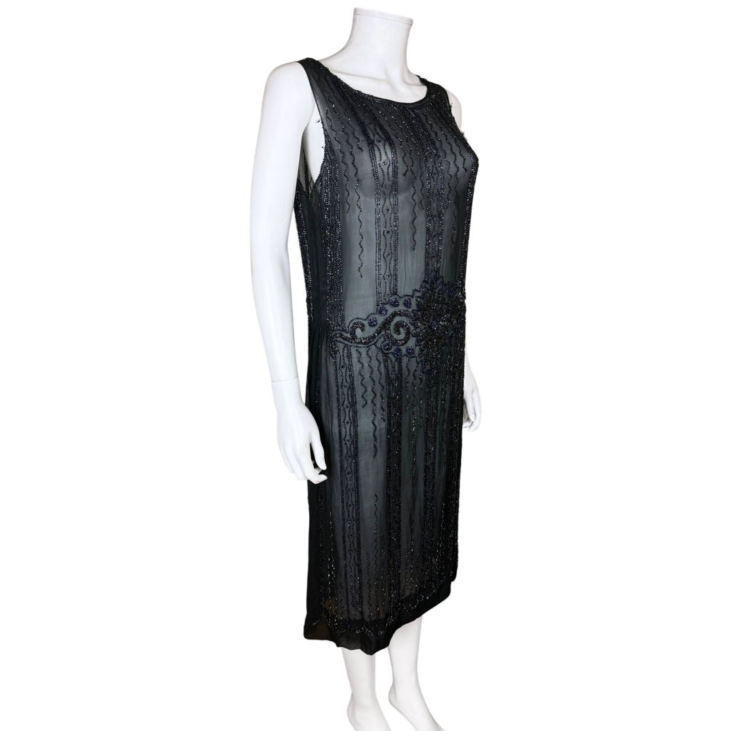 Three-quarter view of 1920s black beaded silk chiffon flapper dress showing loose silhouette and floral waist motif