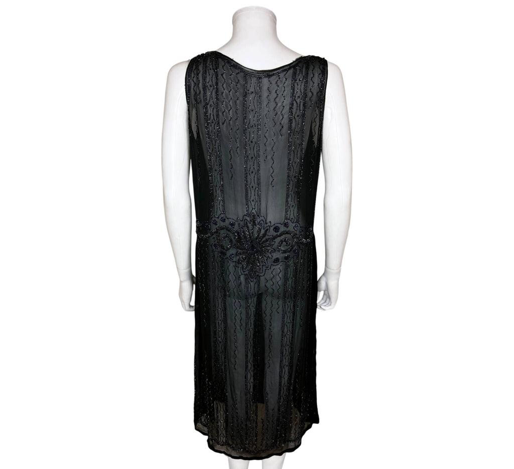 Back view of authentic 1920s black silk chiffon flapper dress with vertical beadwork and decorative dropped waist