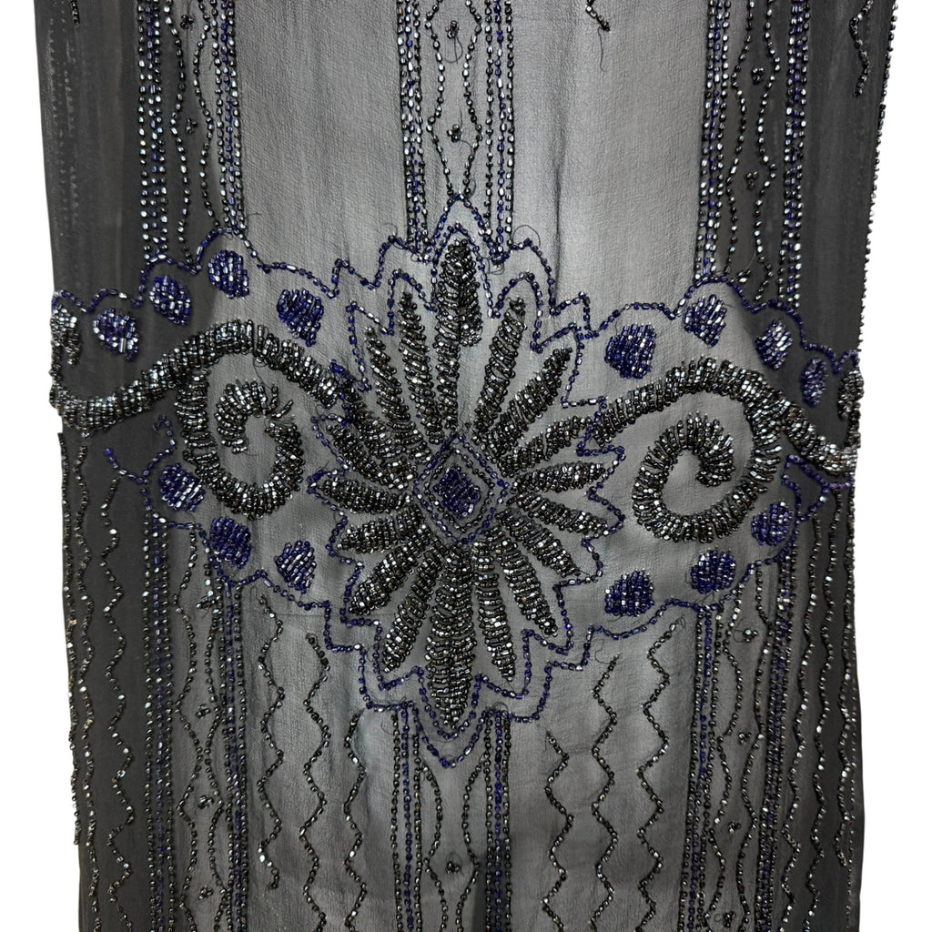 Close-up of 1920s flapper dress showing intricate cobalt blue and gunmetal glass beadwork in floral Art Deco design