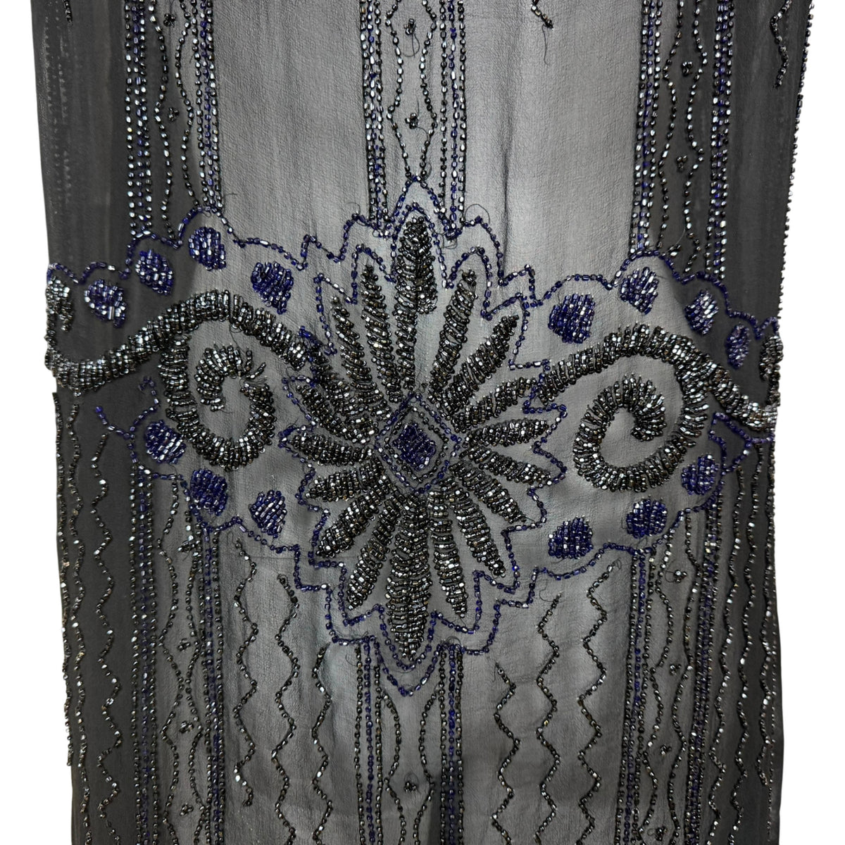 Close-up of 1920s flapper dress showing intricate cobalt blue and gunmetal glass beadwork in floral Art Deco design