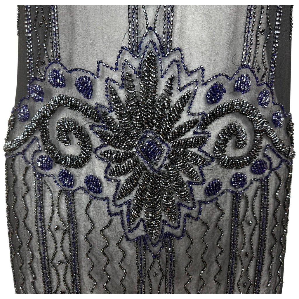 Detailed view of symmetrical scrolling and floral glass bead embroidery on antique 1920s black chiffon dress
