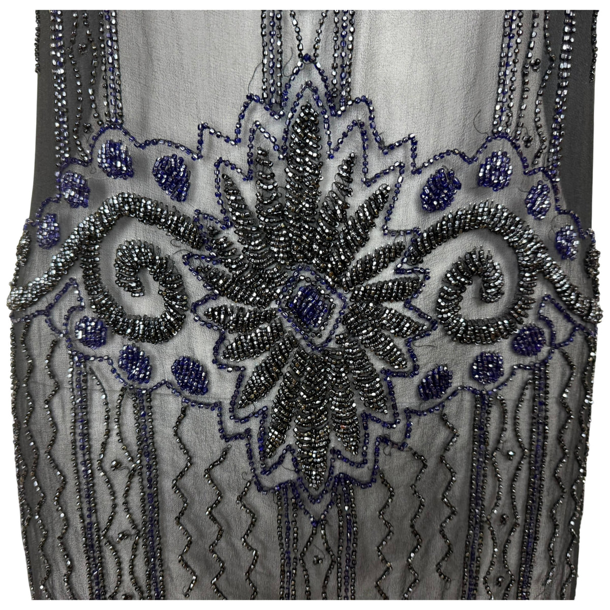Detailed view of symmetrical scrolling and floral glass bead embroidery on antique 1920s black chiffon dress