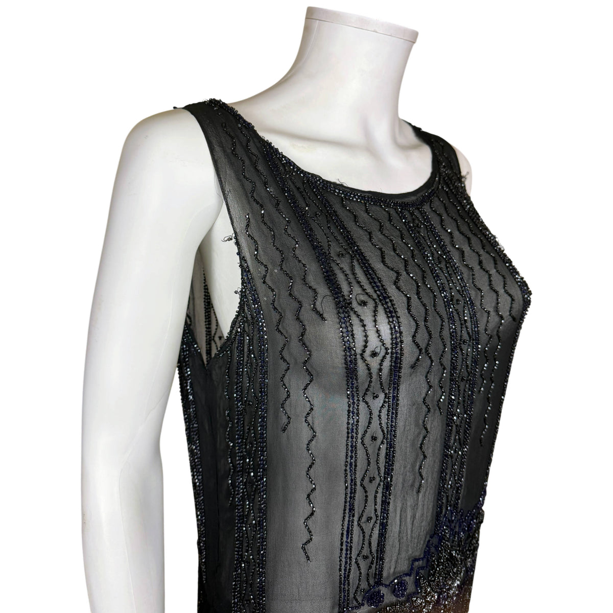 Close-up of neckline, shoulder straps and vertical beaded patterns on 1920s black silk chiffon flapper dress