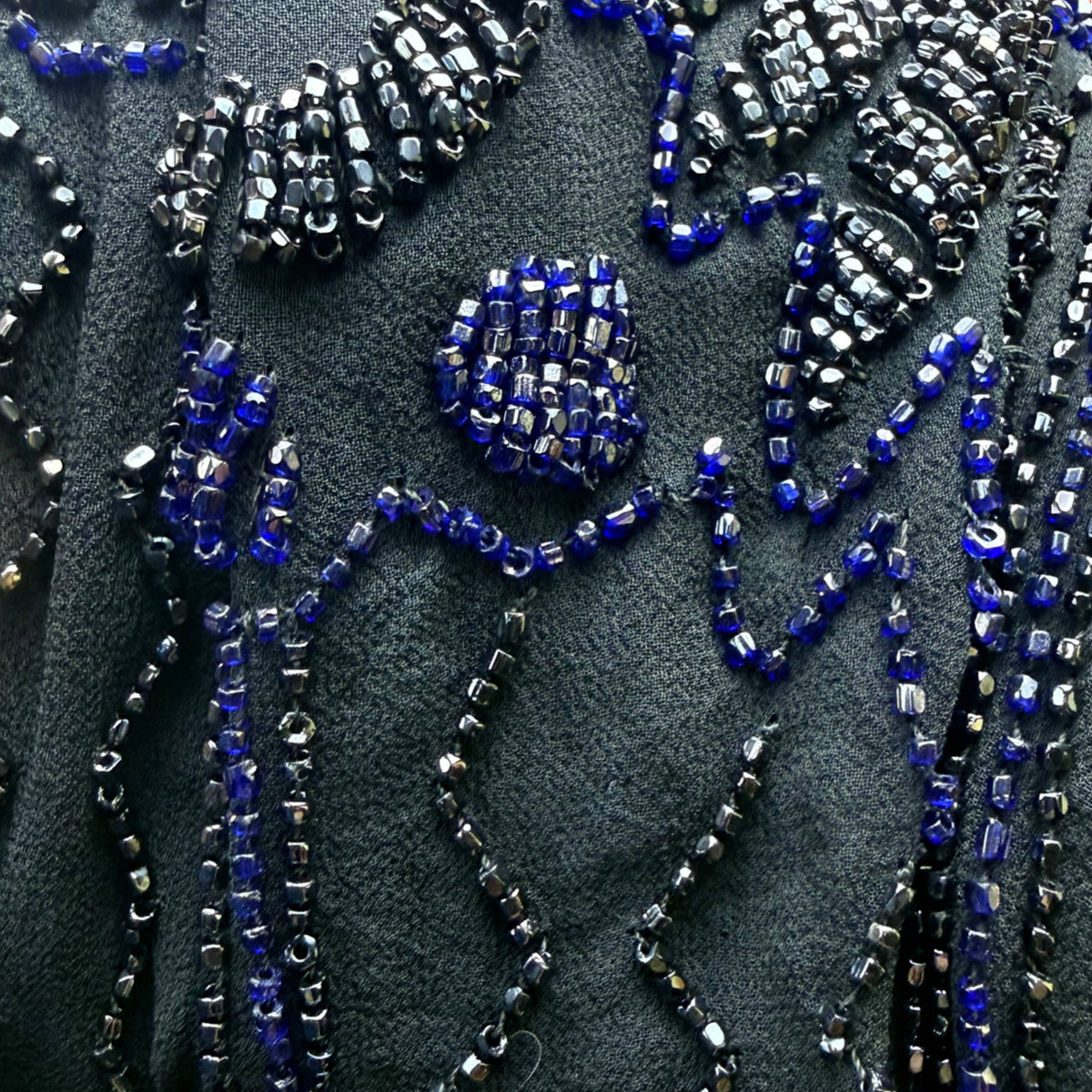 Macro detail of original 1920s glass beadwork in cobalt blue and metallic gunmetal on black silk chiffon