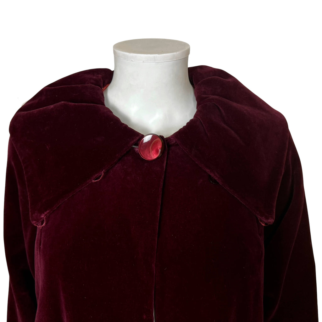 Close-up of burgundy velvet evening coat shawl collar and decorative red button closure