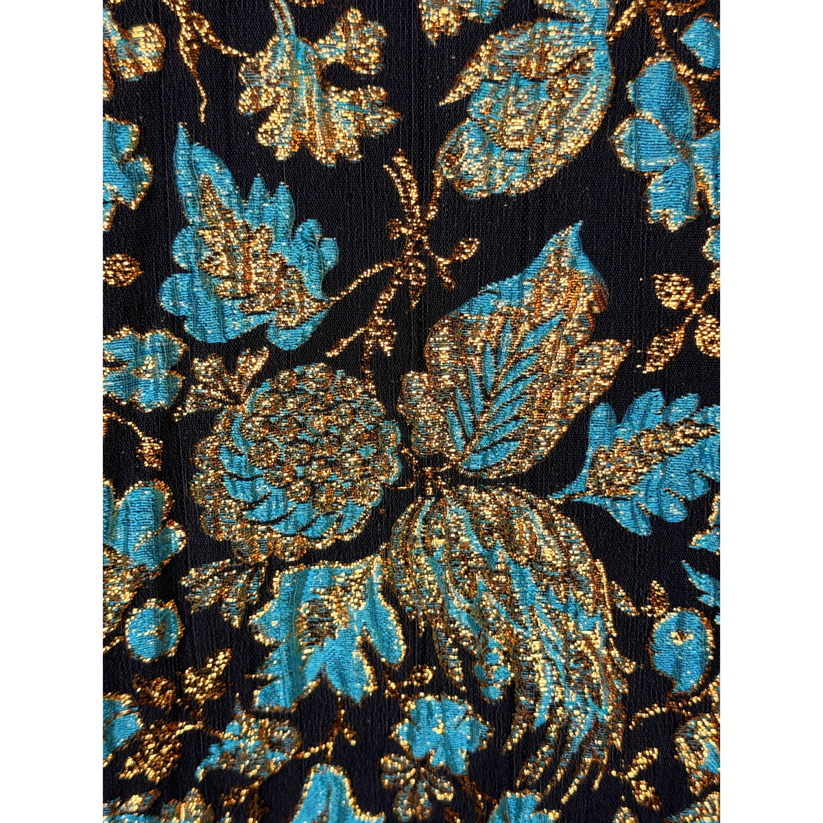 Macro detail of black jacquard brocade with turquoise floral motifs and shimmering metallic gold