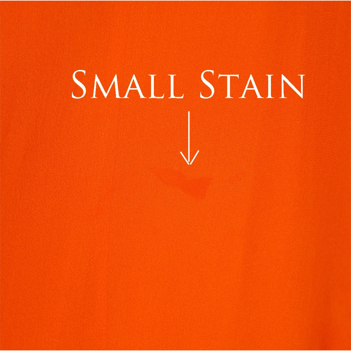 An orange fabric swatch with white text reading 'SMALL STAIN' and a downward arrow pointing to a faint darker stain area near the center.