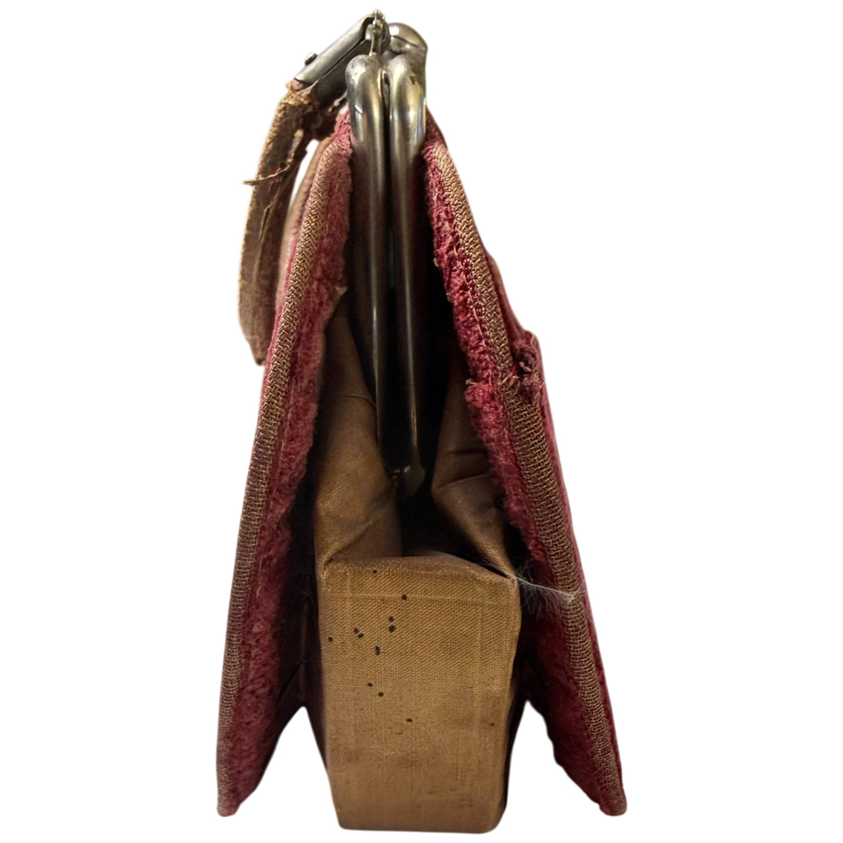 Side view of antique burgundy velvet handbag showing gathered gussets, metal frame and tan interior lining