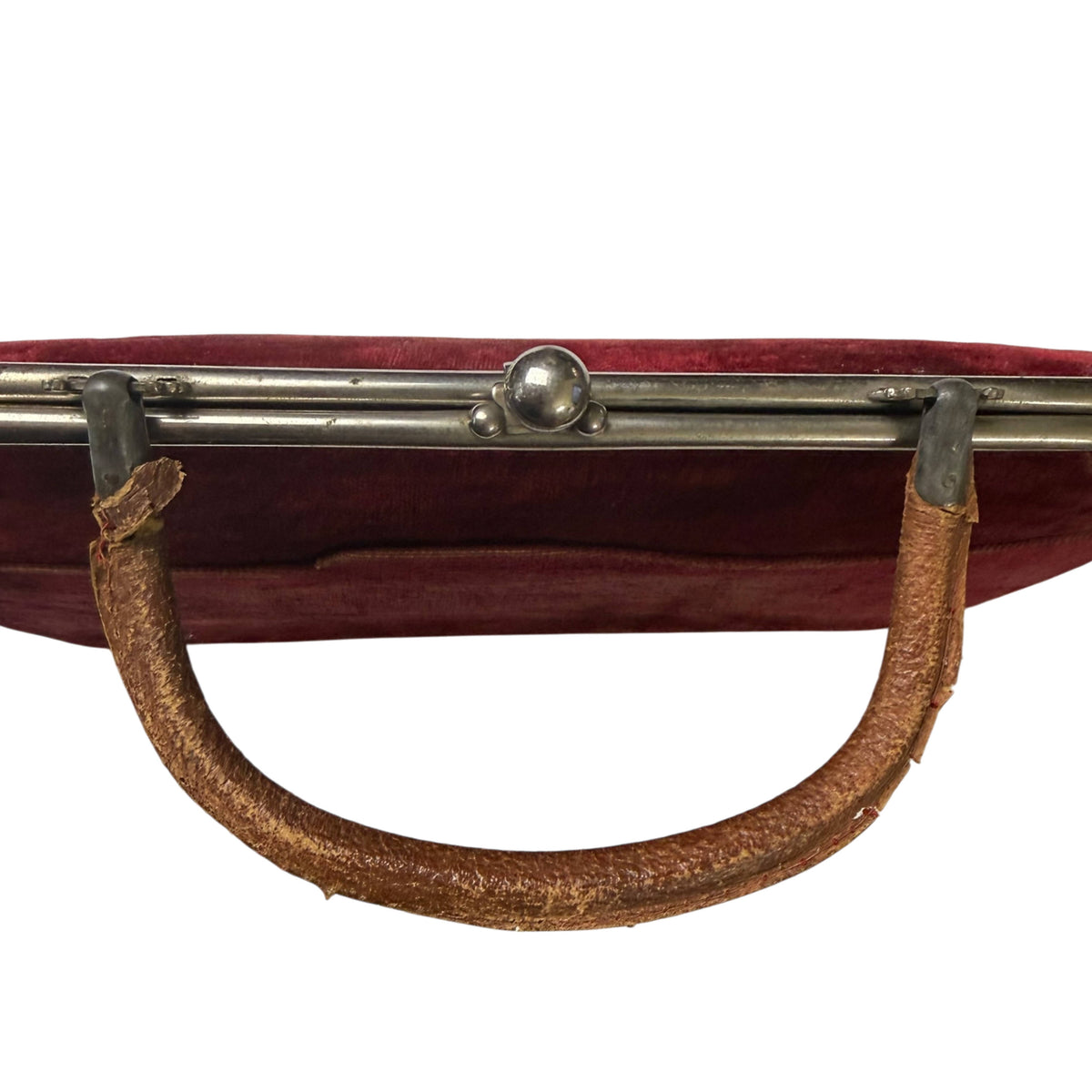 Close-up of antique handbag's curved leather handle showing age-related cracking, abrasion and surface loss