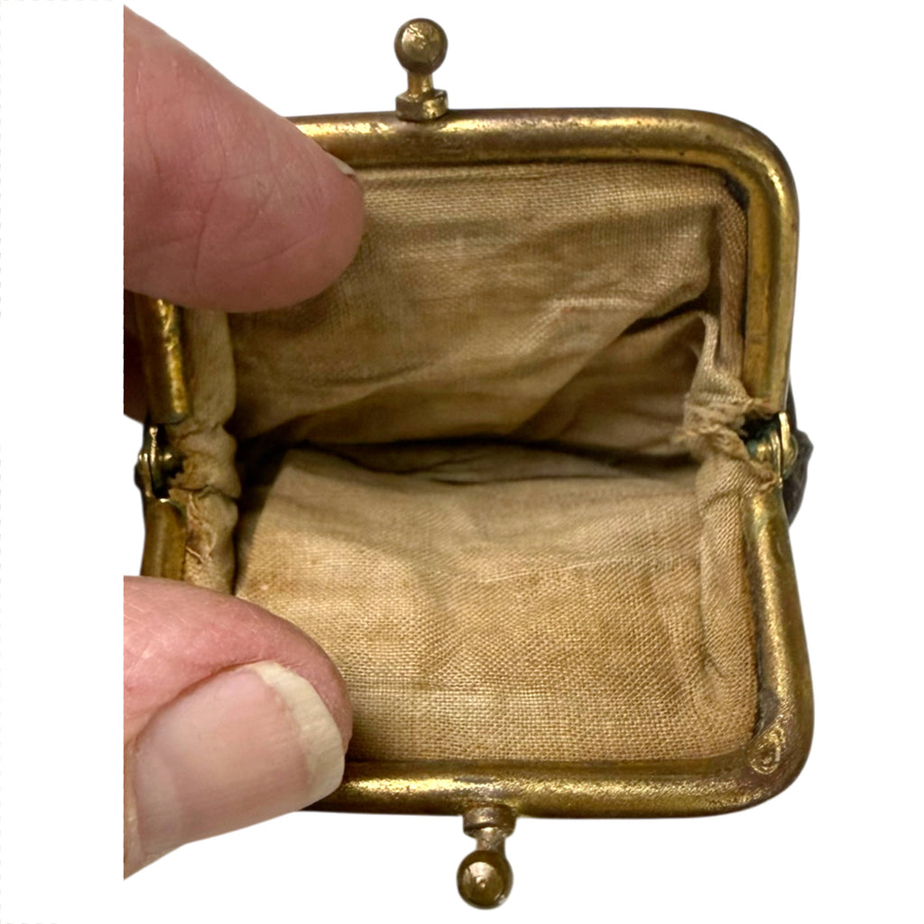 Open antique leather change purse showing tan fabric lining, brass-coloured frame and interior compartment