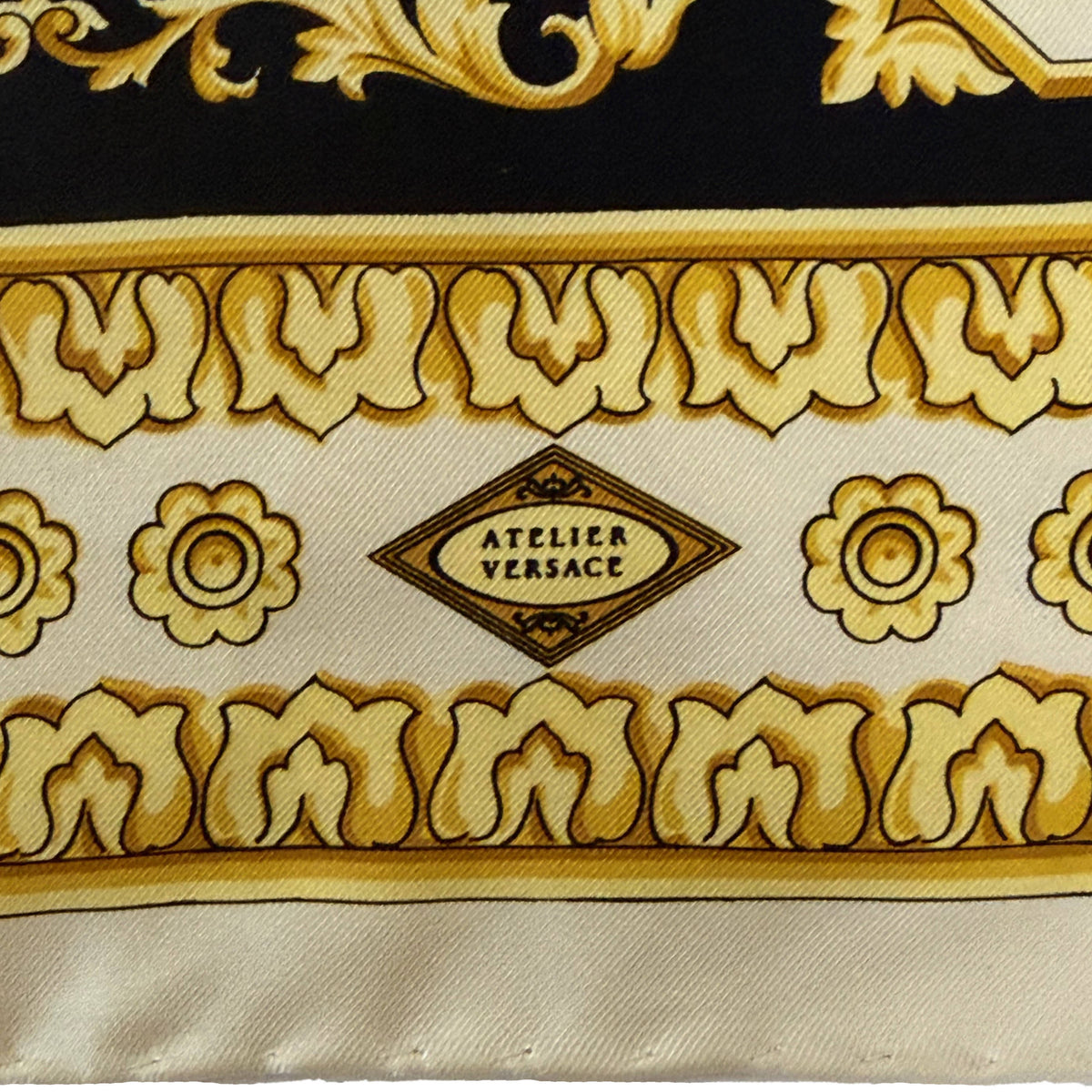 Close-up of Atelier Versace signature printed within decorative border of vintage Italian silk scarf