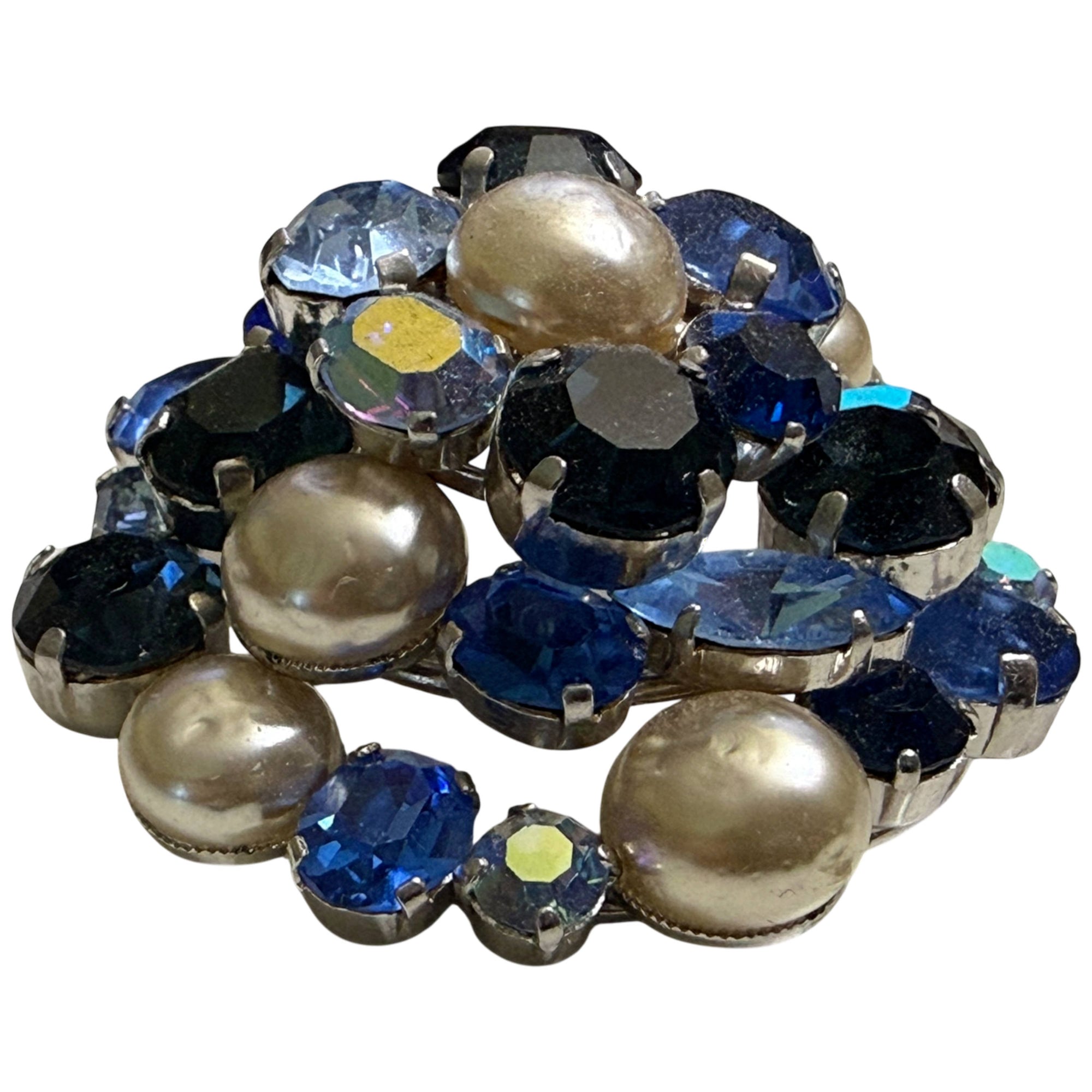 Angled view of blue rhinestone and champagne faux pearl brooch