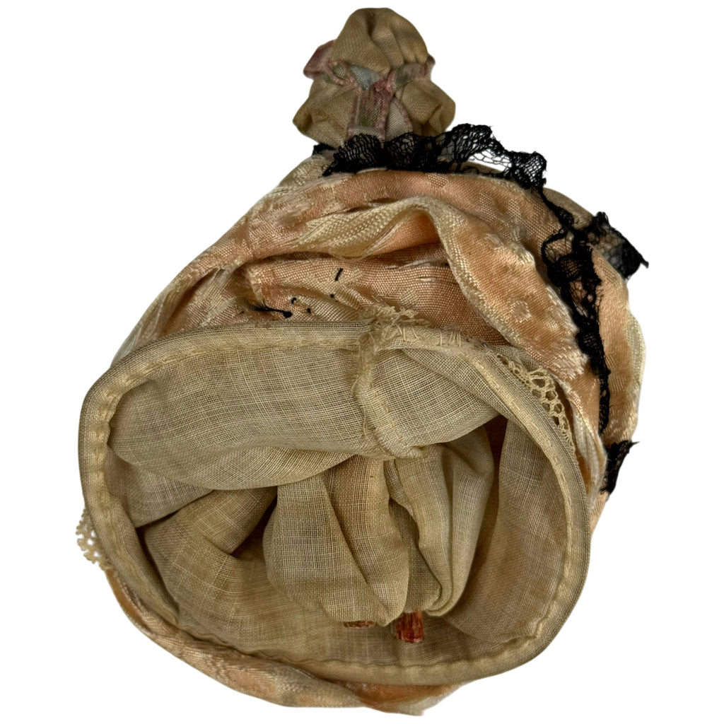 Back and underside of antique Grödnertal doll showing layered cotton undergarments and full silk skirt