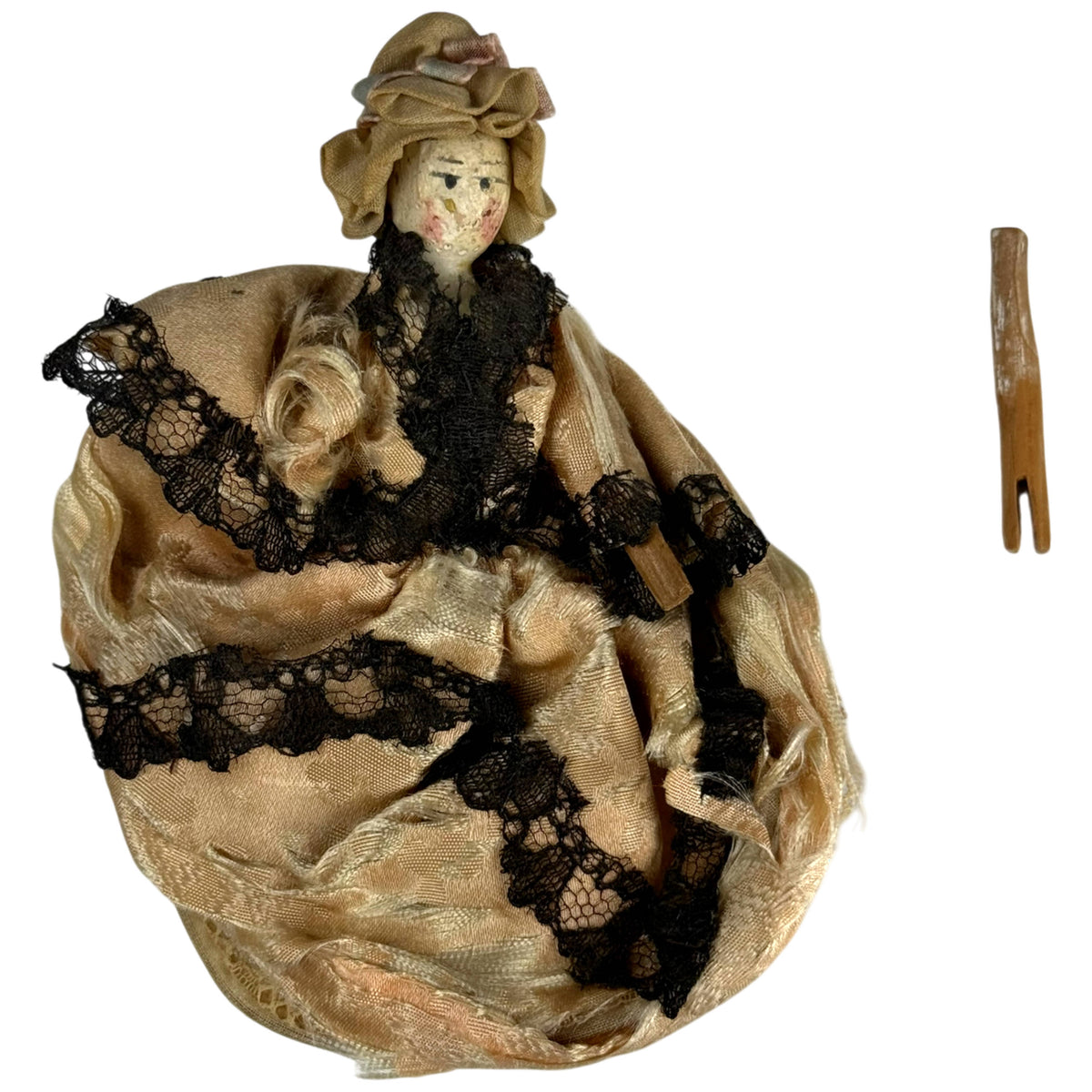 Front view of antique German Grödnertal peg doll showing detached arm and original cream silk ball gown