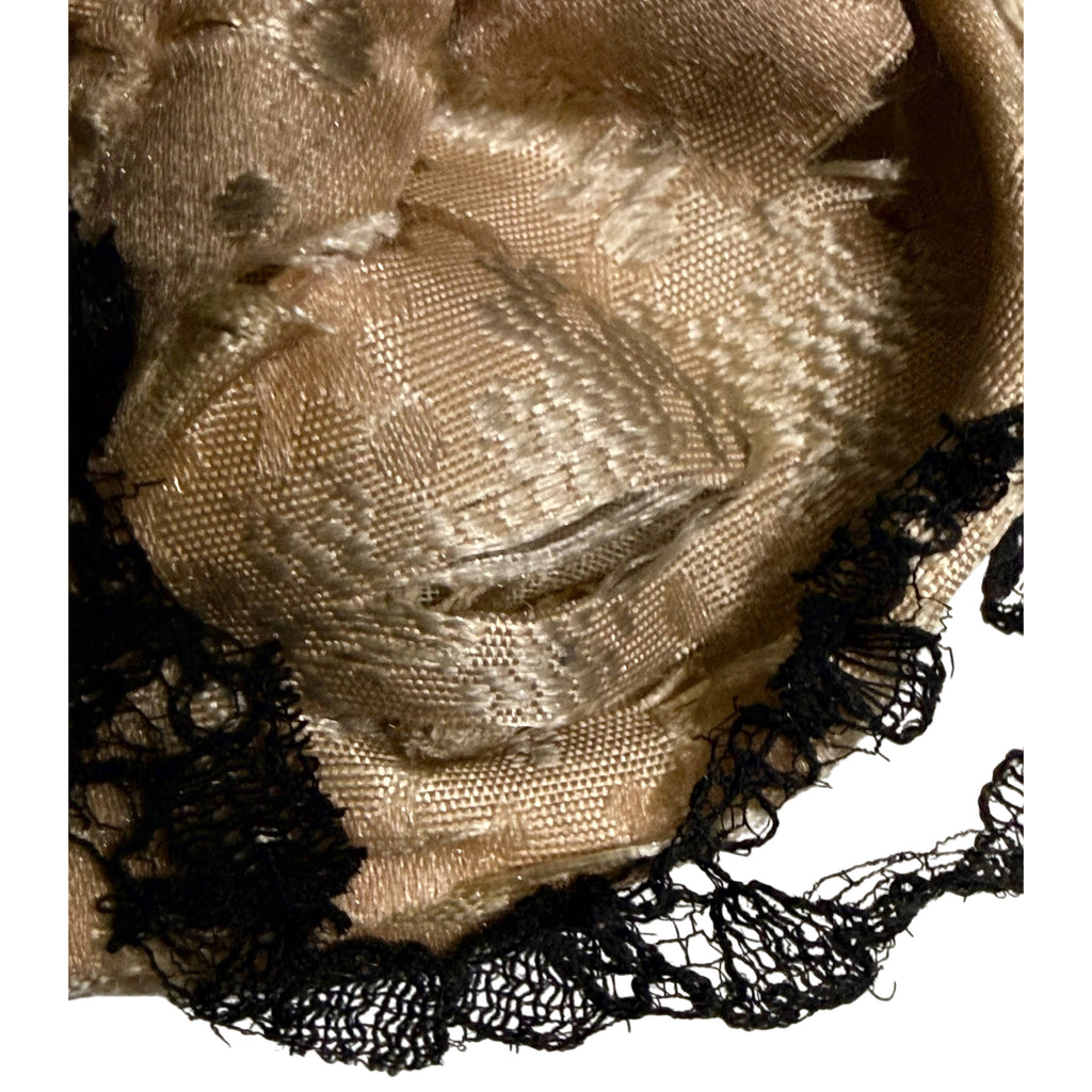 Close-up of antique silk ball gown showing woven floral pattern, fabric splitting and black lace trim