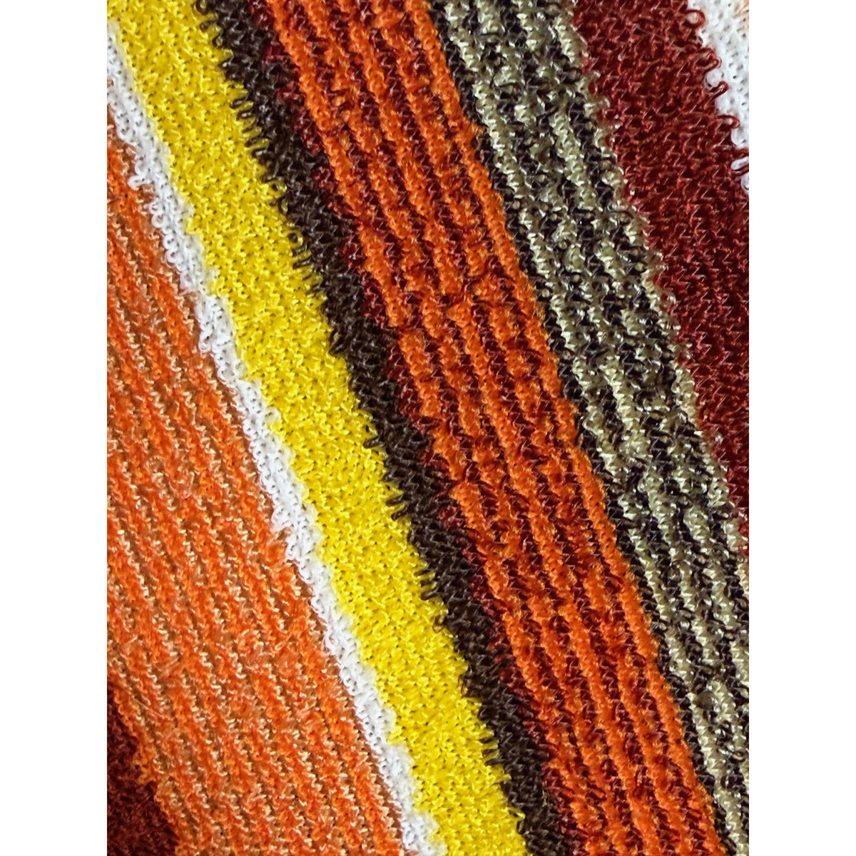 Macro photograph of textured acetate and nylon knit showing orange, yellow, green and burgundy stripes