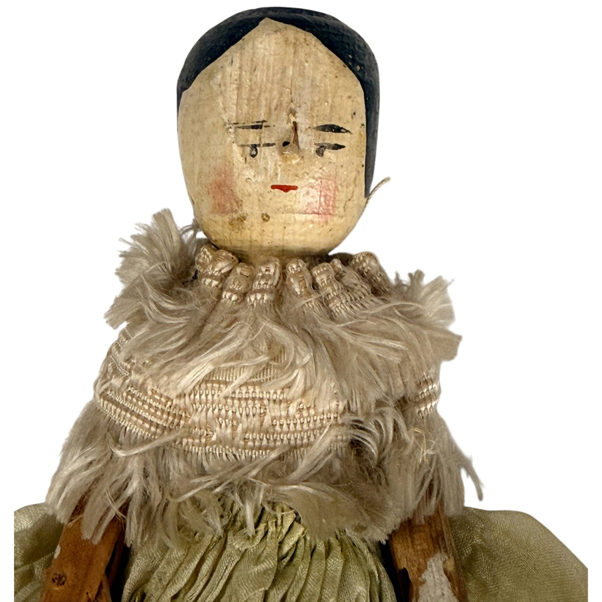 Close-up of antique Grödnertal doll showing hand-painted face, black hair and cream silk fringed bodice trimming
