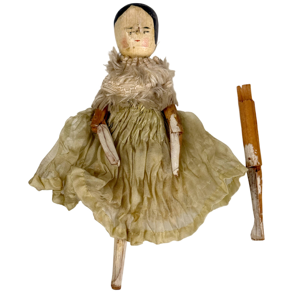 Antique German wooden peg doll in silk dress with detached wooden leg displayed alongside the doll