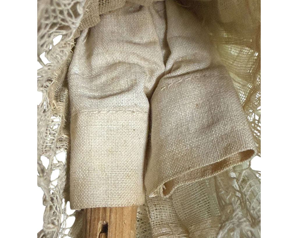 Detail of pale woven fabric pantaloons beneath the silk skirt of an antique German Grödnertal wooden doll.