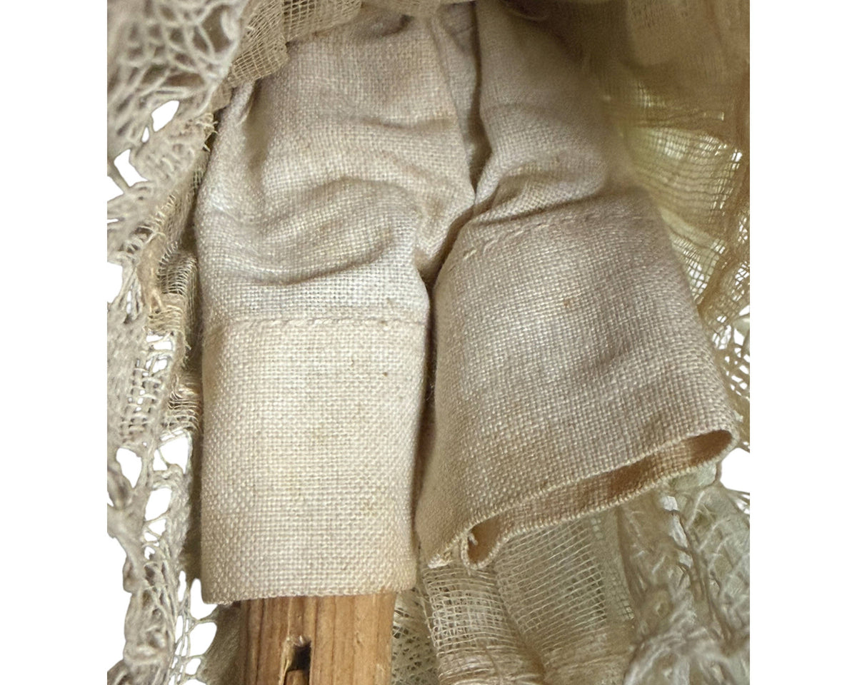 Detail of pale woven fabric pantaloons beneath the silk skirt of an antique German Grödnertal wooden doll.