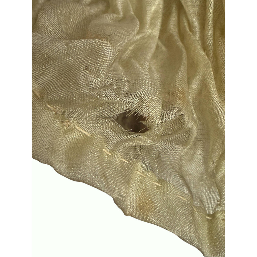 Close-up of fine green-toned silk chiffon skirt showing small holes, delicate fabric and aged stitching