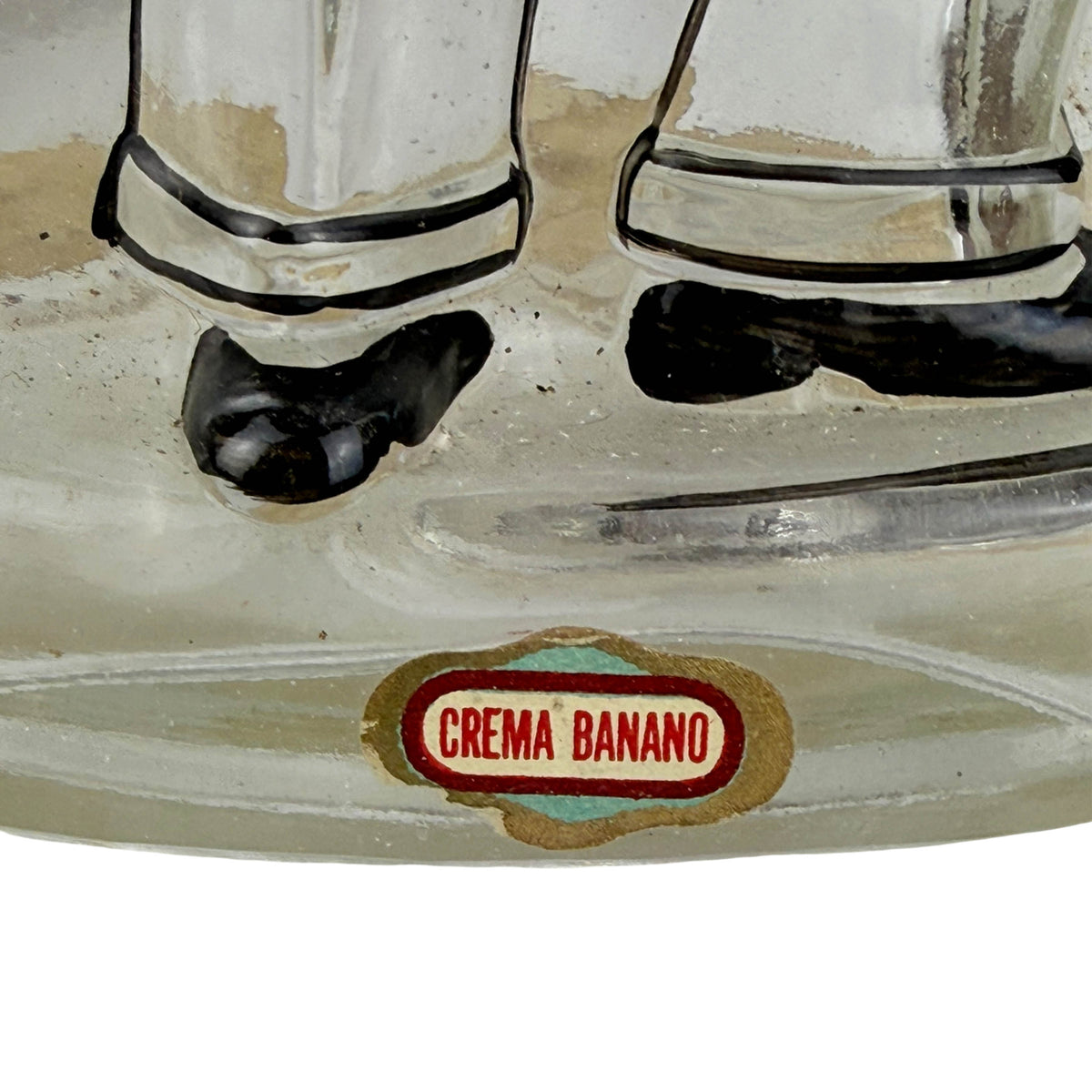 Close-up of a vintage clear glass Cuban bottle with a round 'CREMA BANANO' label on the front