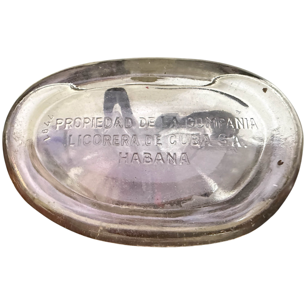 Underside of a clear glass Cuban bottle with embossed Spanish text reading 'Propiedad de la Compania Licorera de Cuba S.A. Habana