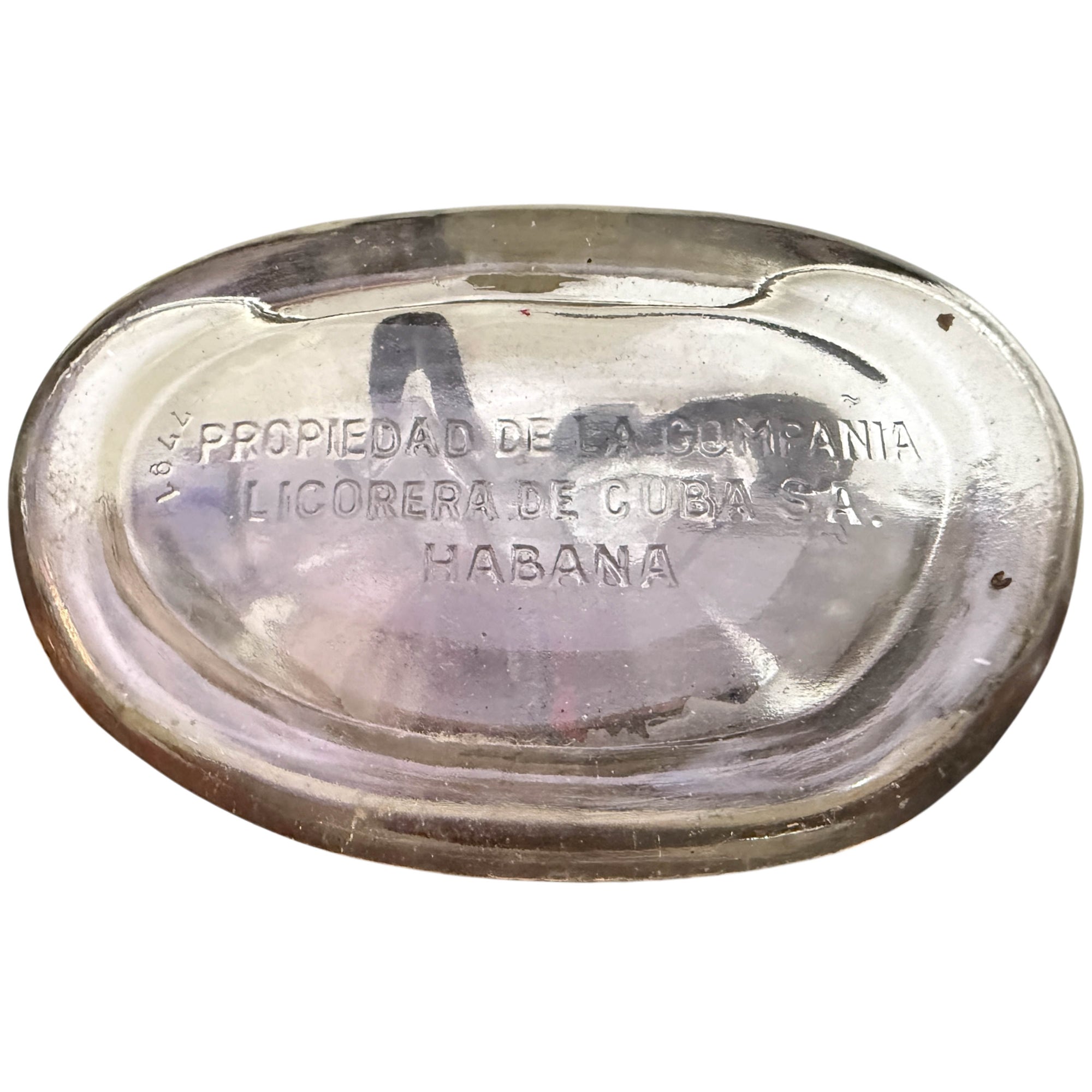 Underside of a clear glass Cuban bottle with embossed Spanish text reading 'Propiedad de la Compania Licorera de Cuba S.A. Habana