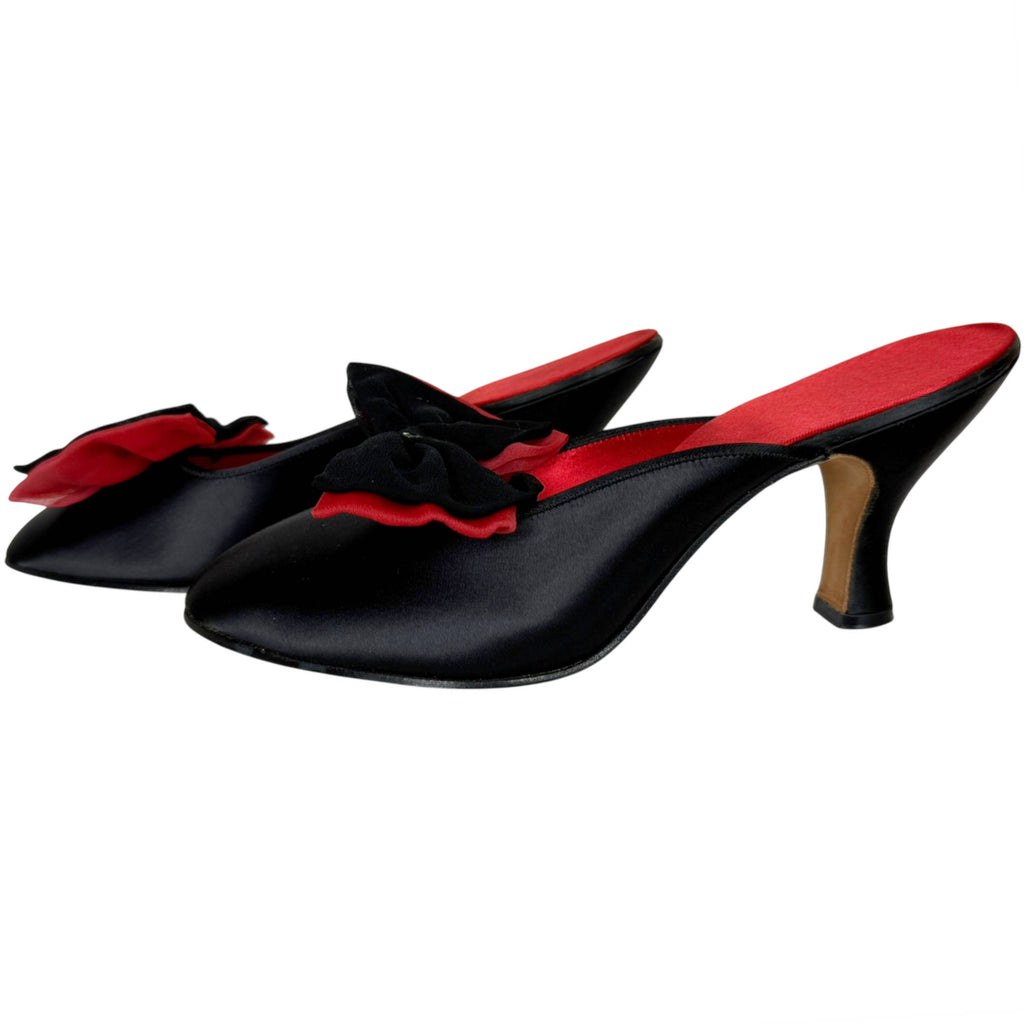 A pair of Daniel Green black satin mule heeled slippers with red lining and a red and black bow detail on the toe, circa 1950s