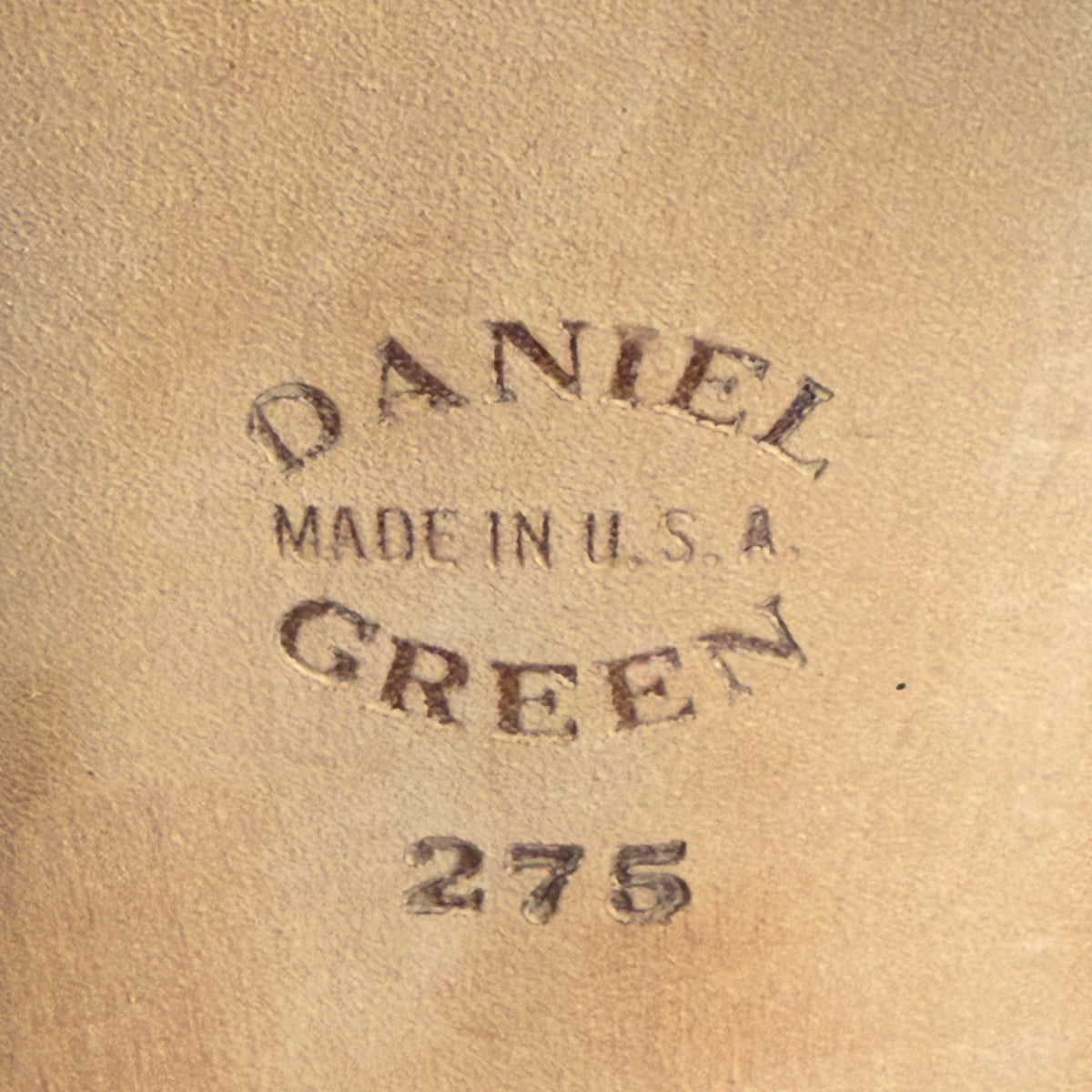 A close-up of slipper sole stamped with the text 'DANIEL GREEN MADE IN U.S.A. 275' 