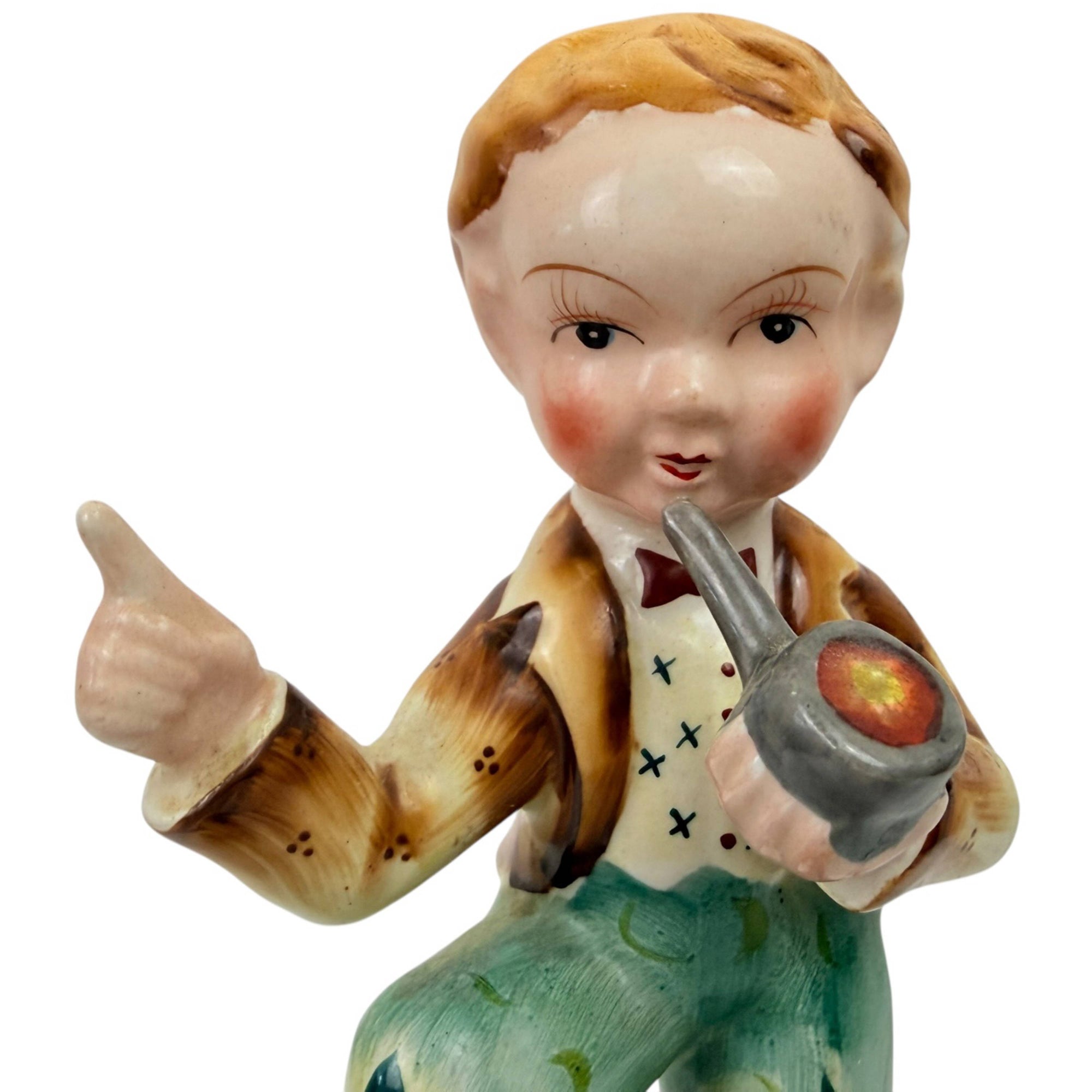 Close view of face of Art Deco pipe boy figurine with rosy cheeks