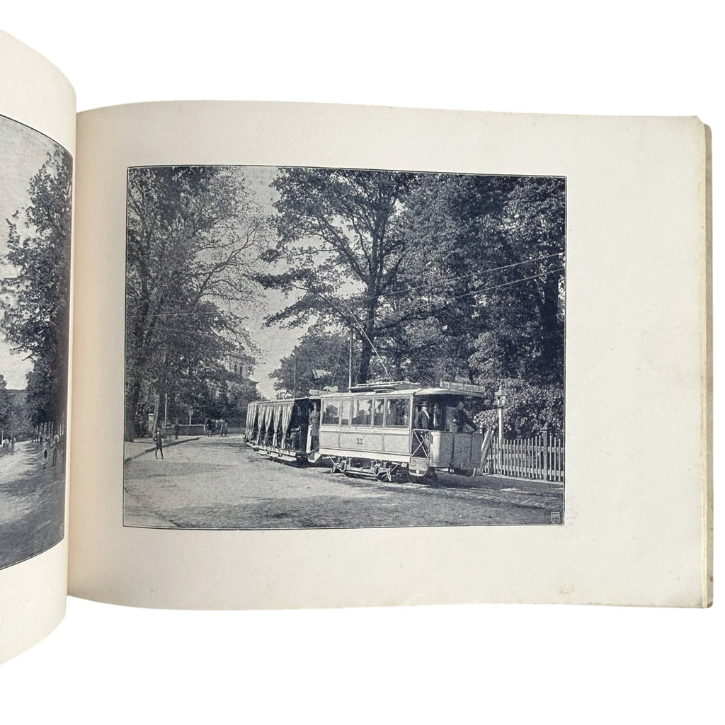 An open 1892 Union Elektricitäts-Gesellschaft book showing a black-and-white photograph of an early electric streetcar traveling along a tree-lined road.