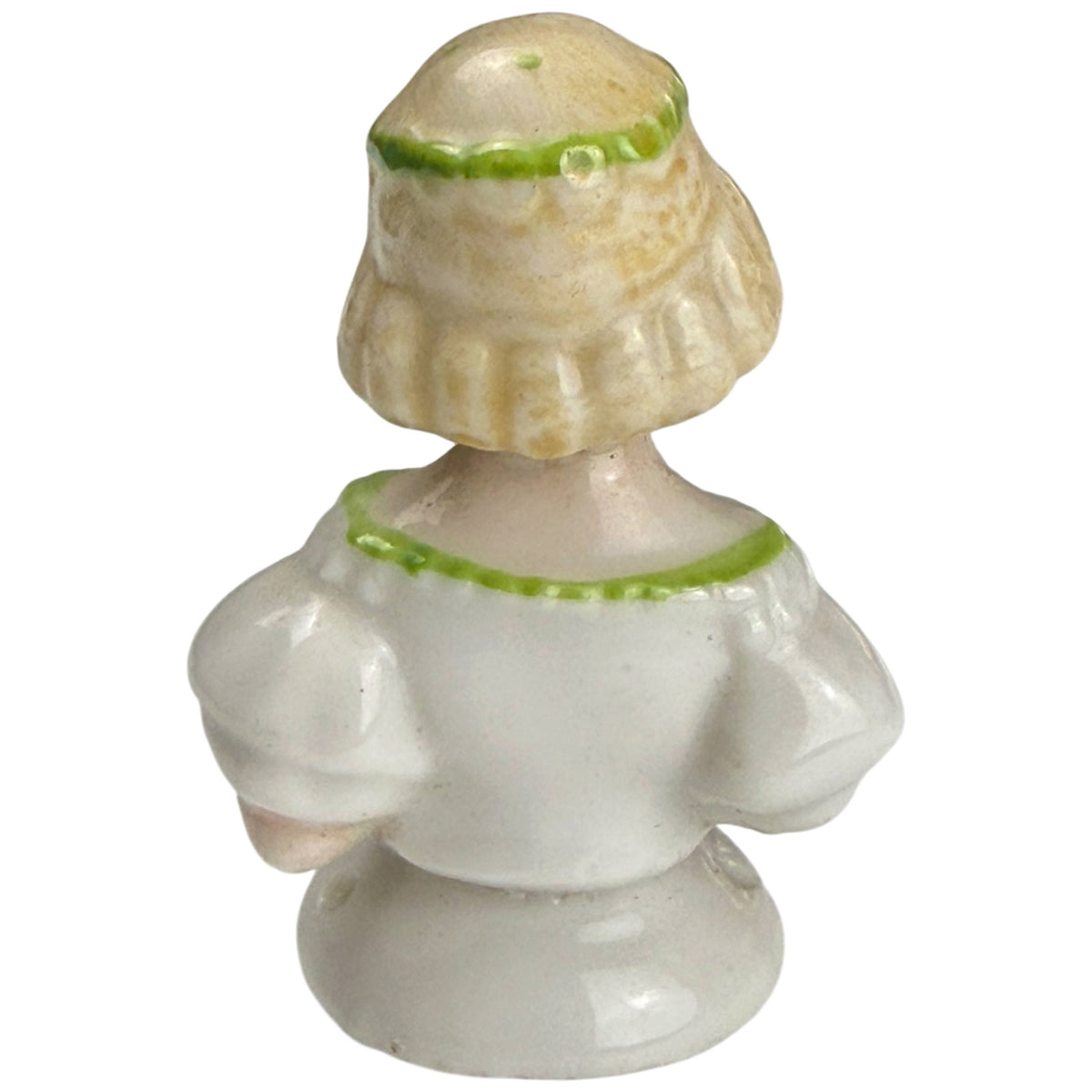 Back view of antique Edwardian-era miniature porcelain half-doll showing blonde bobbed hair, green headband and white puff-sleeve dress