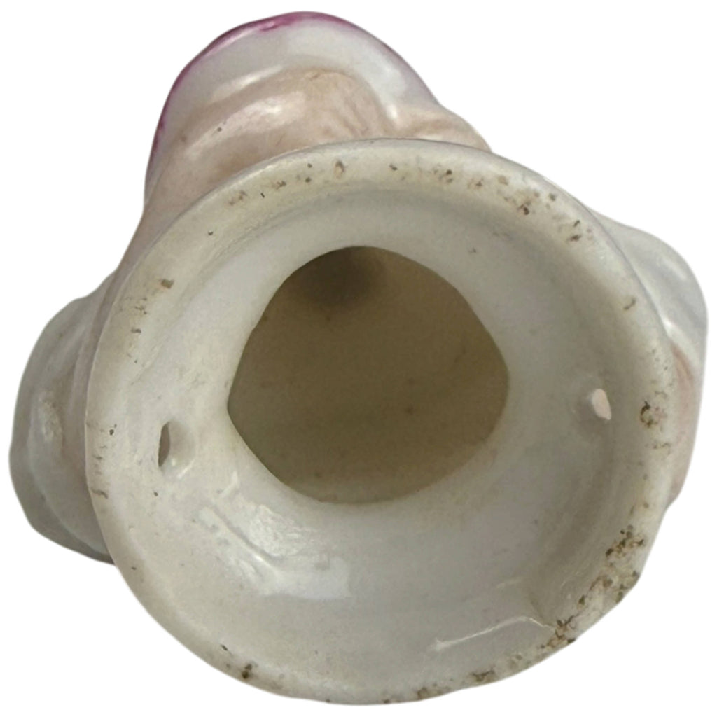 Underside of antique miniature porcelain half-doll showing hollow base and sewing holes for attaching to a pincushion