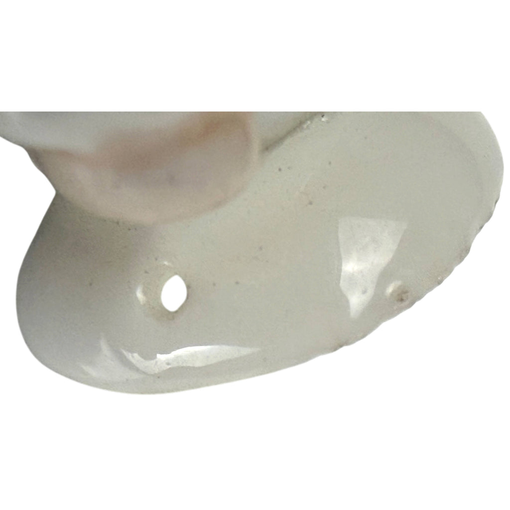 Close-up of porcelain half-doll base showing glazed finish and small sewing hole