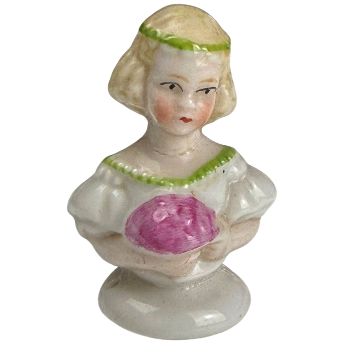Antique miniature German porcelain half-doll bust depicting a blonde girl with green trim holding a pinkish-purple object, front view