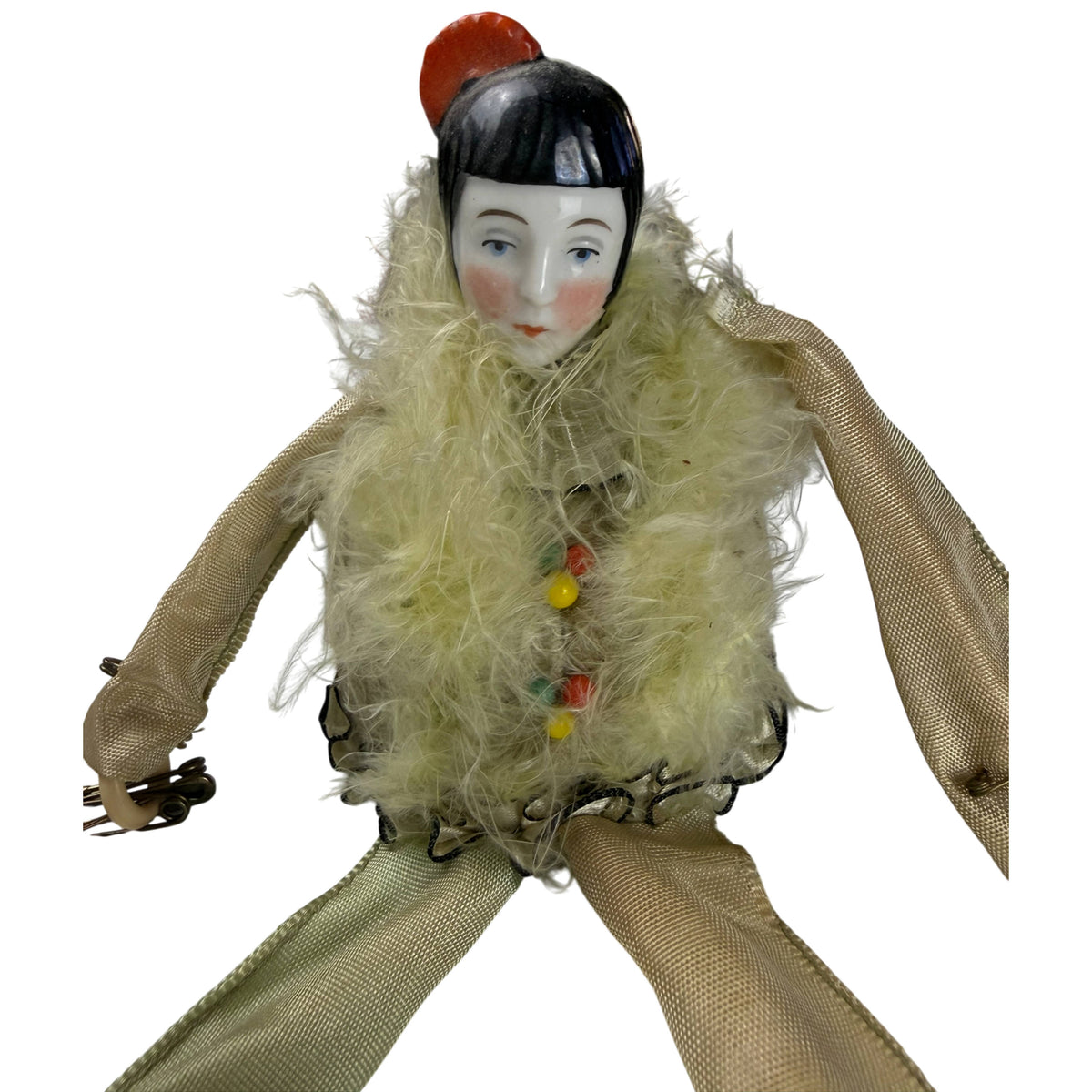 Close-up of 1920s porcelain Pierrot doll with pale green feather trim and coloured bead decorations