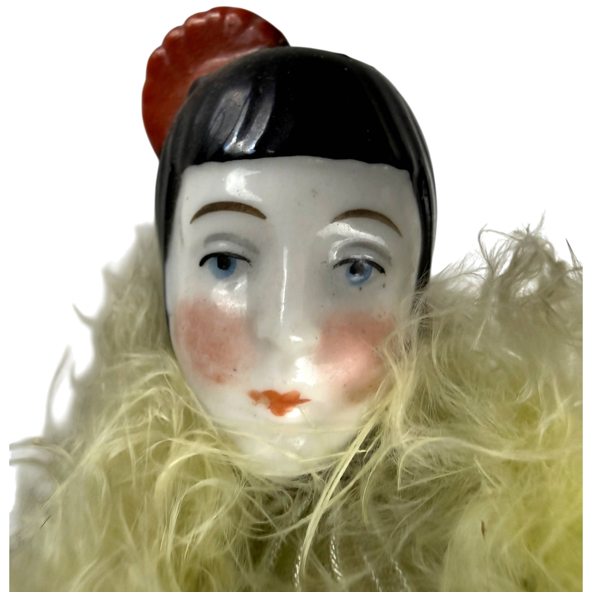 Detail of antique porcelain Pierrot doll face with blue eyes, black moulded hair and red ornament