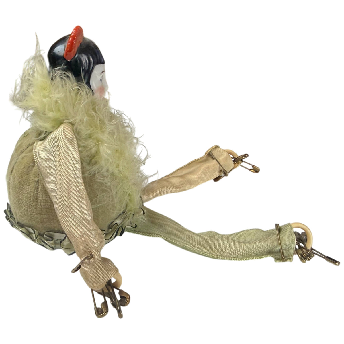 Side view of antique Pierrot pincushion doll showing porcelain head, fabric arms and safety pins