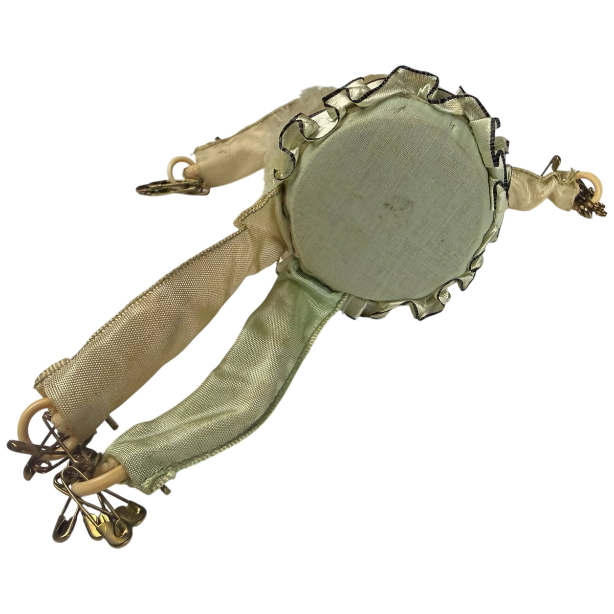 Underside of antique Pierrot pincushion showing circular green fabric base and attached fabric limbs