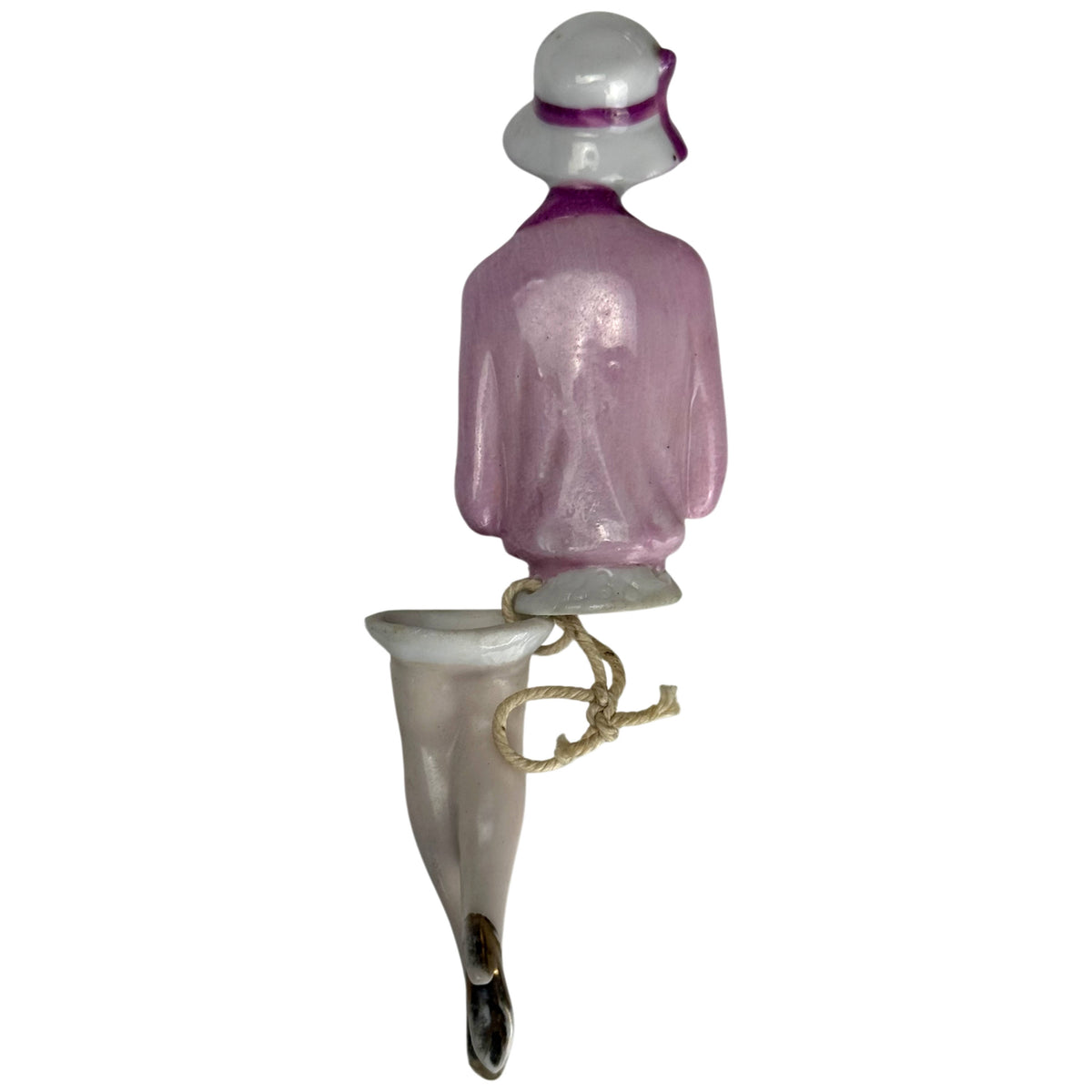 Rear view of antique 1920s porcelain flapper half doll with pink jacket, purple hat trim and attached porcelain legs