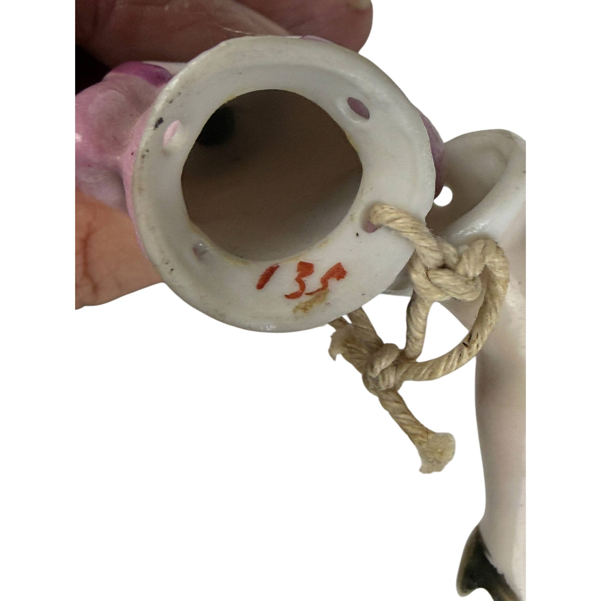 Underside of antique German porcelain half doll showing hand-painted red number 135, attachment holes and original connecting cord