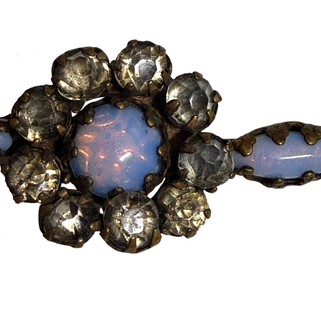 Close-up of Victorian brooch showing central blue opalescent glass cabochon with pinkish flashes and aged paste rhinestones