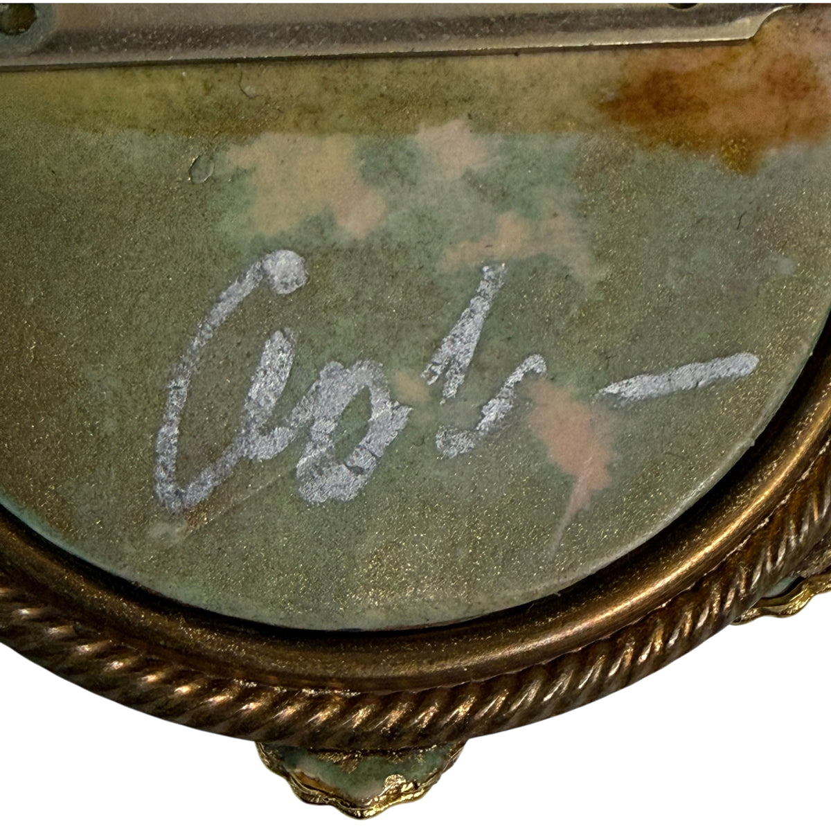 Close-up of silver-coloured artist signature on reverse of brooch