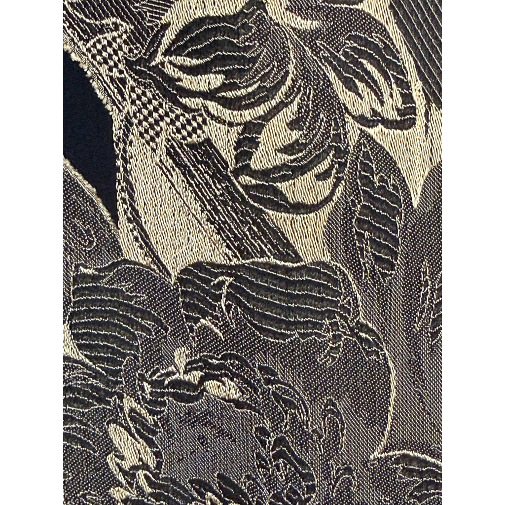 Macro photograph of black and gold jacquard textile showing contrasting woven threads and detailed floral pattern
