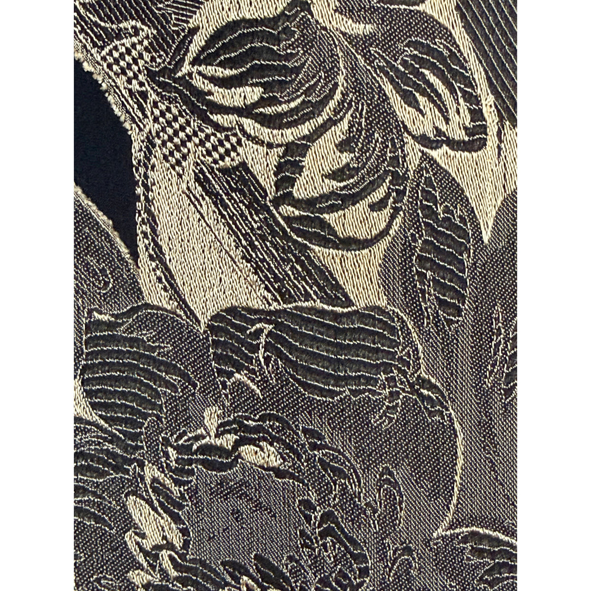 Macro photograph of black and gold jacquard textile showing contrasting woven threads and detailed floral pattern