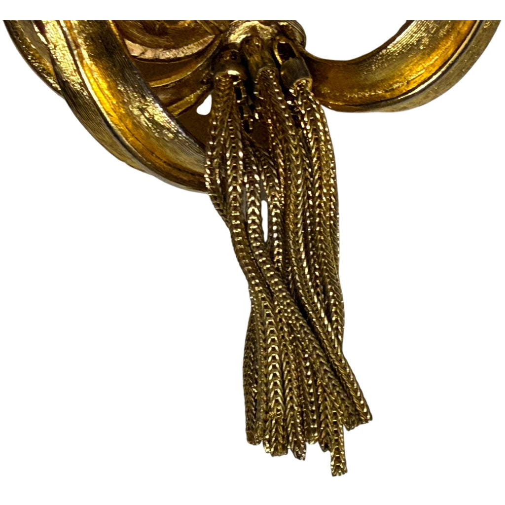 Detail of multiple textured gold-tone chain tassels suspended from Kramer lily brooch