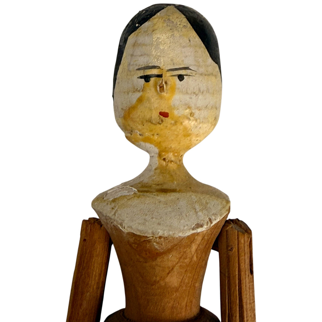 Close-up of antique Grödnertal Dutch doll showing carved wooden head, black painted hair, facial staining and worn original finish.
