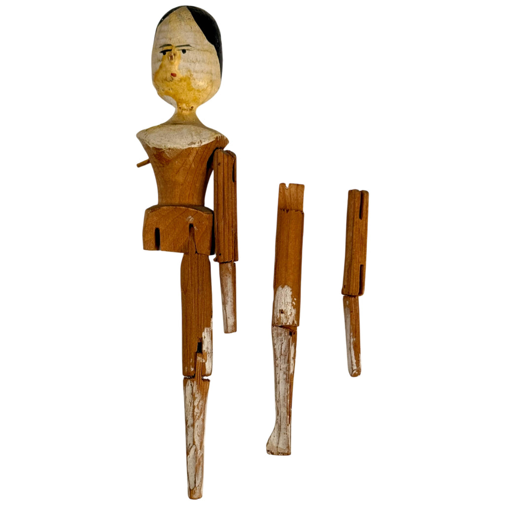 Antique Grödnertal wooden peg doll with detached arm and leg displayed alongside the body, showing traditional wooden joint construction