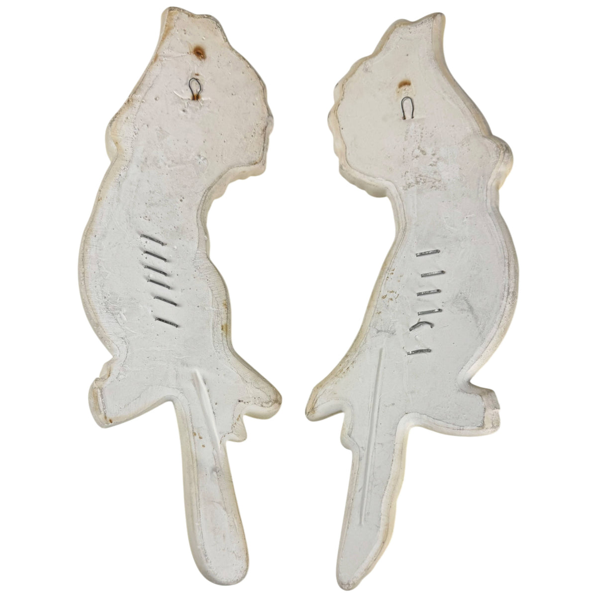 Reverse sides of matching Miller Studio chalkware cockatoo wall plaques showing hanging loops and metal staples.
